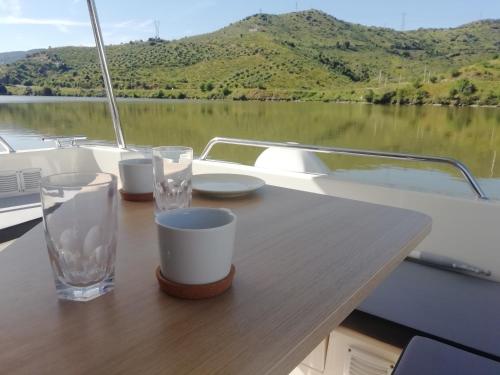a wooden table on a boat with glasses on it at Koolhouse Boat in Vila Nova de Foz Coa