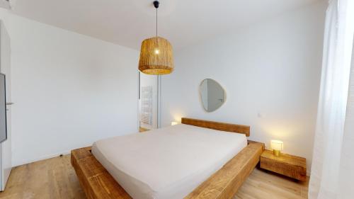 - une chambre avec un lit blanc et une lampe pendant dans l'établissement Villa avec piscine au sel à 50 mètres de la plage, au Cap d'Agde