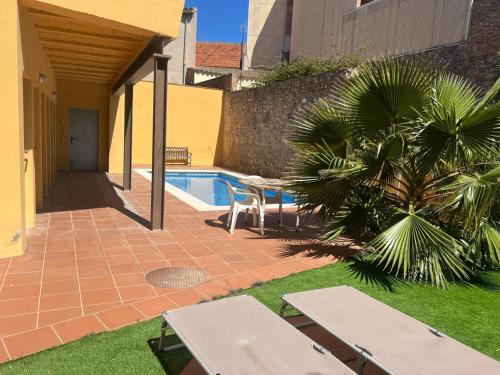 a patio with tables and a palm tree next to a pool at Ground floor apartment in Centre of Torroella De Montgri in Torroella de Montgrí