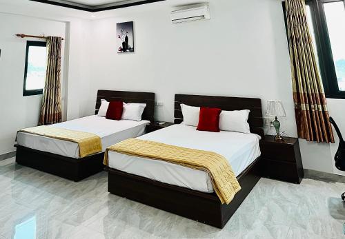 two beds in a room with white walls and windows at Khách Sạn Đông Đô in Hai Phong