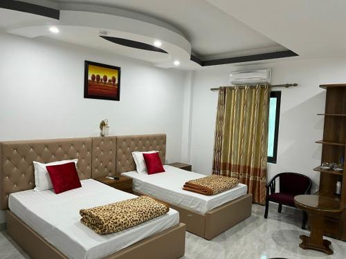 a hotel room with two beds and a chair at Khách Sạn Đông Đô in Hai Phong