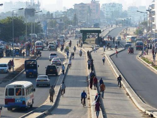um grupo de pessoas andando por uma rua movimentada da cidade em 1 NICOS LODGING em Dar es Salaam