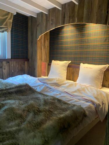 a bedroom with a large bed with a wooden wall at La Kabane des Hetres rouges in Spa