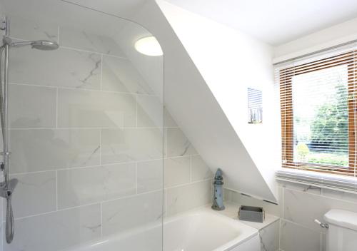 een witte badkamer met een douche en een wastafel bij Ash in Lowestoft