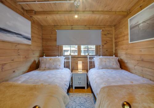 two beds in a room with wooden walls at Old Cottage The Log Cabin in Bacton