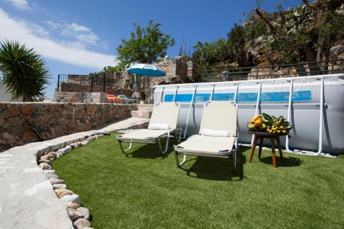two chairs and a table on grass next to a pool at Home Aurora with private pool in Vrachasi