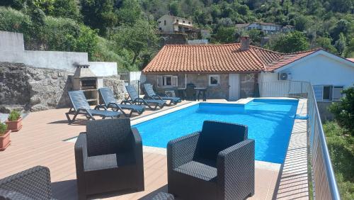 a swimming pool with chairs and a house at Casa do Quitaranda - Gerês in Vieira do Minho