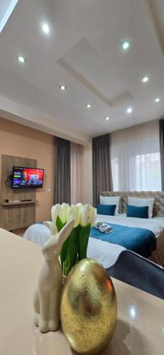 a room with a room with two beds and a vase of flowers at Design Apartment BUSINESS LUX 4 STAR "RIO" Completely Business LUX place in the City Center & FREE INCLUDED Industry optical WiFi & NETFLIX & Keyless code entry & FULL SMART APP & Kitchen & Washing machine & Wide terrace & SECURE 2 Parking place in Ćuprija