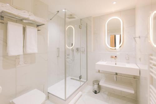 a white bathroom with a shower and a sink at H&ocirc;tel Majestic in Bordeaux