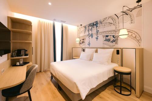 ボルドーにあるオテル マジェスティックの白いベッドとデスクが備わるホテルルームです。