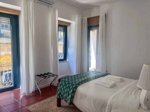 ein weißes Schlafzimmer mit einem Bett und zwei Fenstern in der Unterkunft Imperial Douro Apartamento 1 in Peso da Régua