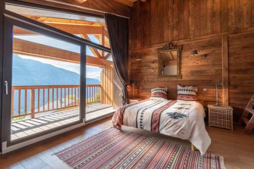 a bedroom with a bed and a large window at Chalet Apalosa - Montvalezan, La Rosière in Montvalezan