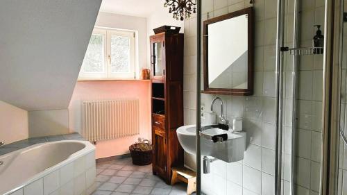 y baño con bañera, lavabo y espejo. en FeWo "Altes Schulhaus" Oberstaufen/Höfen, en Oberstaufen