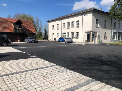 a parking lot in front of a white building at Logis - Hotel Restaurant La Sapinière in Wisques
