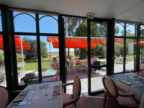 uma sala de jantar com mesas, cadeiras e janelas em Logis - Hotel Restaurant La Sapinière em Wisques