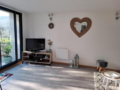 a living room with a tv and a heart on the wall at Les glycines in Salles-la-Source