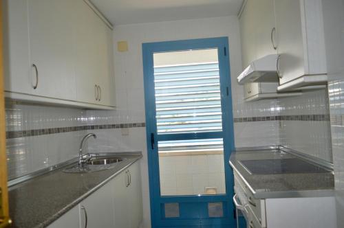 a kitchen with a sink and a blue door at Teatinos Atico Penthouse Pool WiFi Parking in Málaga