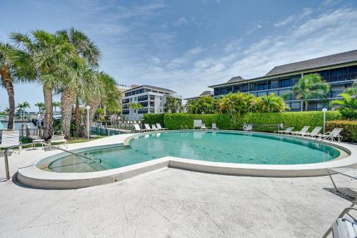 a swimming pool with chairs and trees and a building at Waterfront Marco Island Condo Less Than quarter Mi to Beach! in Marco Island