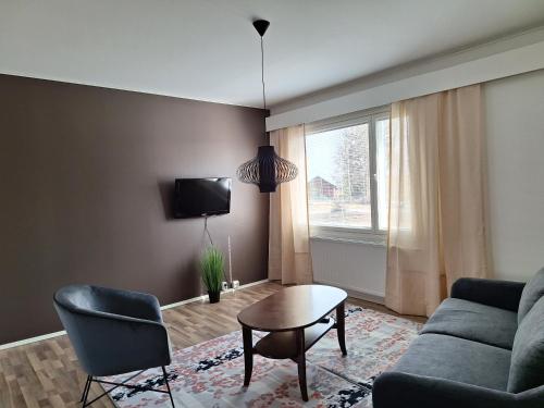 ein Wohnzimmer mit einem Sofa, einem Tisch und einem Fenster in der Unterkunft Jääskän Loma, Kojolapark asunto 2 in Voltti