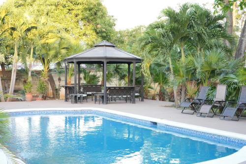 a gazebo with a table and chairs next to a pool at 中国人之家公寓酒店Apart-Hotel Casa de China in Managua
