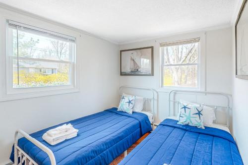 two beds in a room with two windows at Calm Seas Cottage in Falmouth