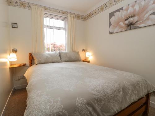 a bedroom with a white bed and a window at Blorenge in Abergavenny