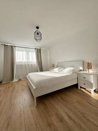 une chambre blanche avec un grand lit et une fenêtre dans l'établissement Joli appartement dans une maison remise à neuf, à Mittelhausbergen