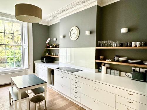 a kitchen with white cabinets and a table and a clock at Harrington Apartments in Central London in London
