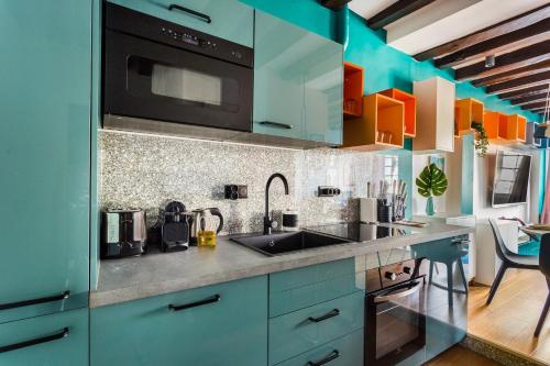 a kitchen with blue cabinets and a sink and a microwave at Central Apartment - Shopping at your Doorstep in Paris