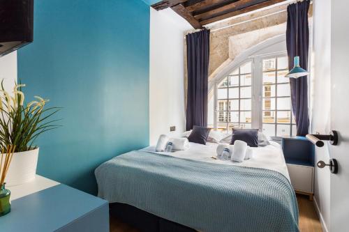 ein blaues Schlafzimmer mit einem Bett und einem Fenster in der Unterkunft Central Apartment - Shopping at your Doorstep in Paris