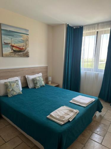 ein Schlafzimmer mit einem blauen Bett und Handtüchern darauf in der Unterkunft Sea stars Kaliakria resort in Topola