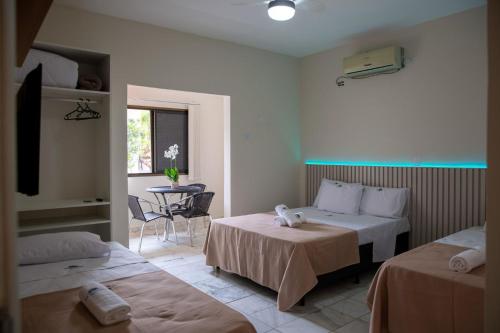 a hotel room with two beds and a table at Pousada Sol da Enseada Guarujá in Guarujá