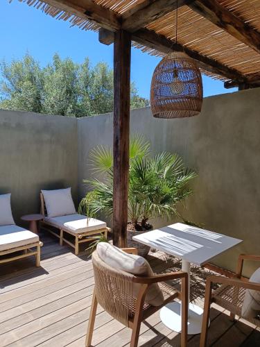 a patio with a table and chairs on a deck at Hôtel Les Suites Du Maquis in Bonifacio