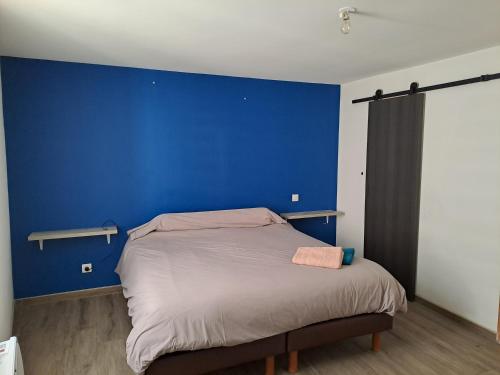 Bett in einem Zimmer mit blauer Wand in der Unterkunft Agréable maison climatisé in Le Soler