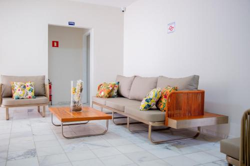 a living room with two couches and a table at Pousada Sol da Enseada Guarujá Inn - Piscina Aquecida in Guarujá