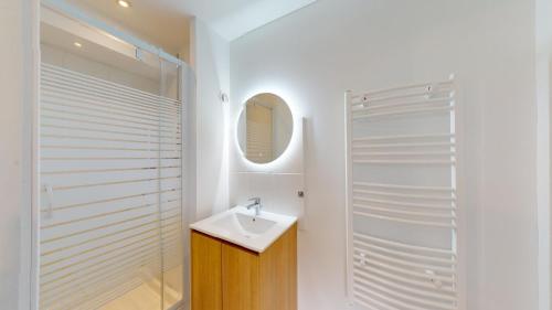 een witte badkamer met een wastafel en een douche bij Immeuble COTY Jacuzzi studios et chambres in Le Havre