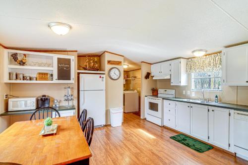 a kitchen with white cabinets and a wooden table with a wooden floor at Nancy Cabin with Fire Pit Near Lake Cumberland! in Nancy