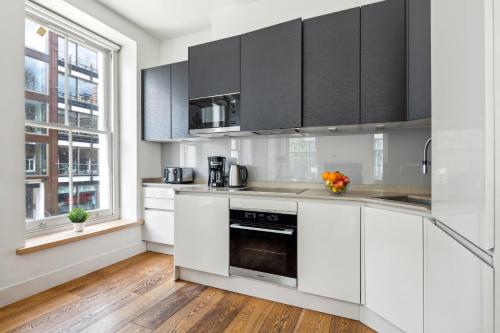 a kitchen with white cabinets and an oven at Fitzrovia 3BR - CityApartmentStay in London