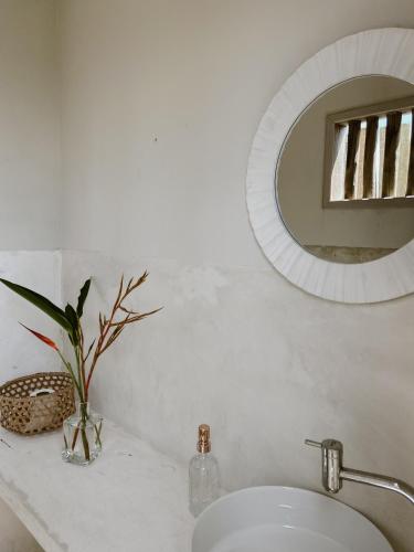 a white bathroom with a sink and a mirror at Pousada Refazenda in Corumbau