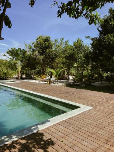 a swimming pool next to a wooden deck and trees at Pousada Refazenda in Corumbau