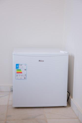 a white refrigerator sitting on a floor next to a wall at Pousada Sol da Enseada Guarujá Inn - Piscina Aquecida in Guarujá