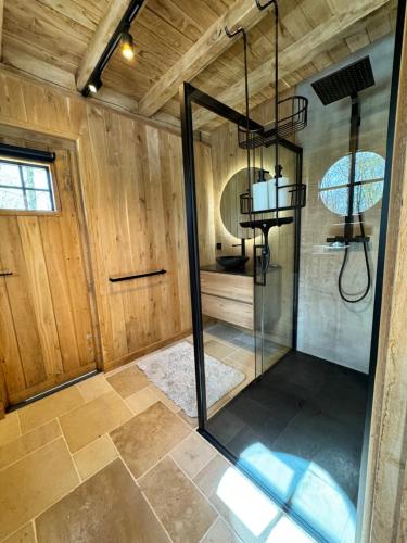 una ducha con puerta de cristal en una habitación en Magnifique chalet en bois avec piscine et jacuzzi en Court-Saint-Étienne