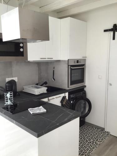 a kitchen with white cabinets and a black counter top at La maison Anaïa in Gargas
