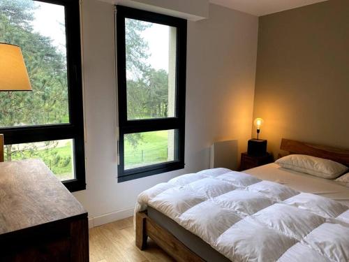 une chambre avec un grand lit avec deux fenêtres dans l'établissement Bienvenue au Green, à Neufchâtel-Hardelot