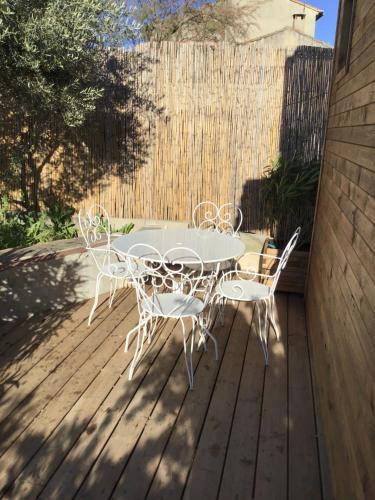 a white table and chairs on a wooden deck at La maison Anaïa in Gargas