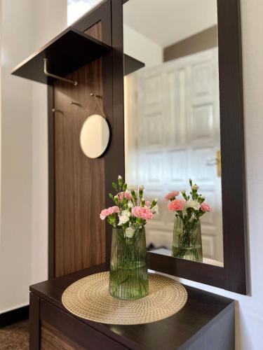 two vases with flowers on a table in front of a mirror at AgroDomek Rzepiska in Rzepiska