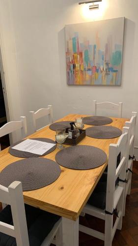 a wooden table with white chairs and a painting at Hermoso Departamento con Balcón Obelisco II in Buenos Aires