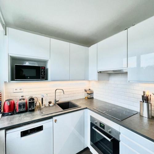 eine weiße Küche mit einer Spüle und einer Mikrowelle in der Unterkunft Shiny apartment - Direct line to Olympic Village in Clichy
