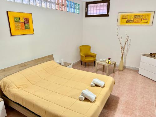 a bedroom with a large bed and a yellow chair at A Casa di Anto - 90 mq con parcheggio interno Animal friendly in Infernetto