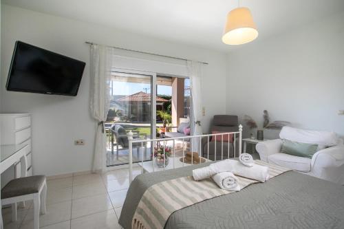 a bedroom with a bed and a television and a balcony at Sea Breeze & Nature villa ,near the sea, luxury jagguzi and spa private garden in Kremasti